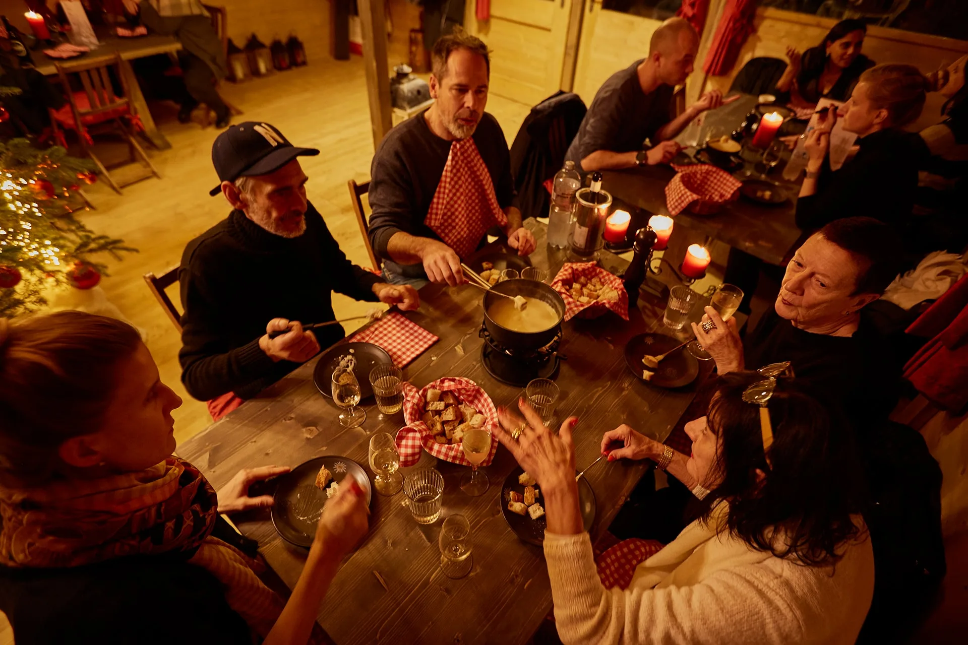 Gruppe beim Käsefondue an einer langen Tafel im Fondue Chalet, Zürich